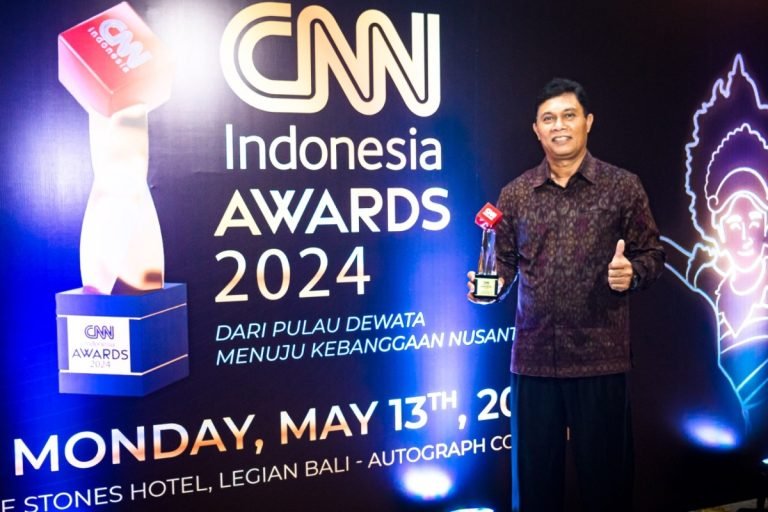 General Manager PT PLN (Persero) UID Bali I Wayan Udayana menyempatkan berpose sambil memegang trofi di depan podium ajang CNN Indonesia Award 2024