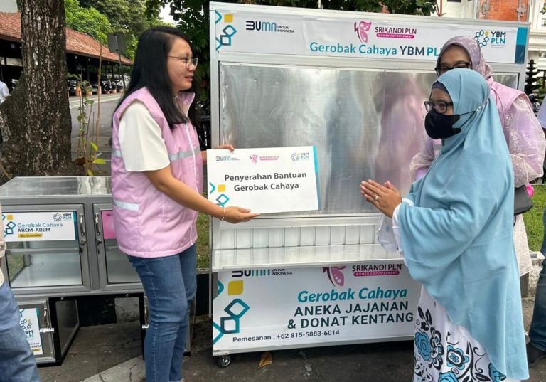 Ketua Srikandi PT PLN (Persero) Unit Induk Distribusi (UID) Bali Ni Made Sumaryani menyerahkan plakat simbolis bantuan gerobak cahaya kepada salah satu penerima bantuan Oktovianti.