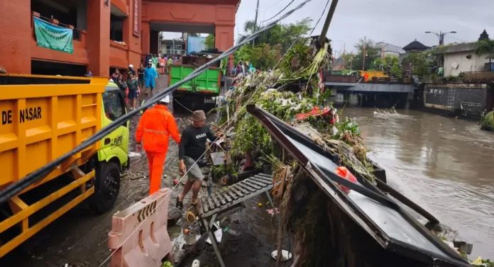 Petugas PLN berjibaku lakukan penanganan tiang listrik roboh tergerus longsor akibat cuaca hujan di pasar Kumbasari Denpasar.