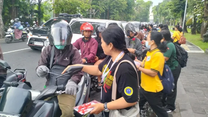 Komisi Penanggulangan AIDS (KPA) Kota Denpasar bersama Dinas Kesehatan Kota Denpasar memperingati Hari AIDS Sedunia (HAS) 2025 dengan membagikan bunga mawar dan brosur edukasi kepada masyarakat yang melintas di kawasan Catur Muka Denpasar, Senin (1/12).