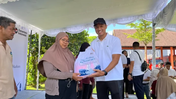 General Manager PT PLN (Persero) UID Bali, Eric Rossi Priyo Nugroho saat memberikan paket sembako tebus murah ke salah satu masyarakat yang hadir pada program tersebut.