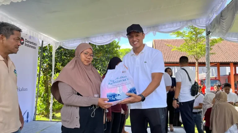General Manager PT PLN (Persero) UID Bali, Eric Rossi Priyo Nugroho saat memberikan paket sembako tebus murah ke salah satu masyarakat yang hadir pada program tersebut.