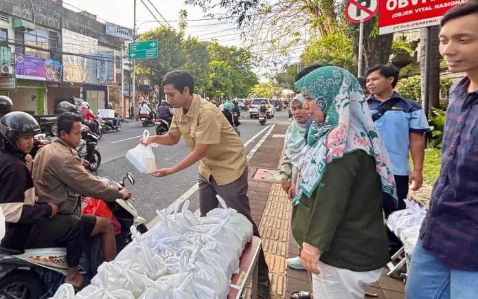 Suasana pembagian iftar dan takjil kepada pengendara motor di depan kantor oleh pegawai PLN UP2D Bali menjelang berbuka puasa.