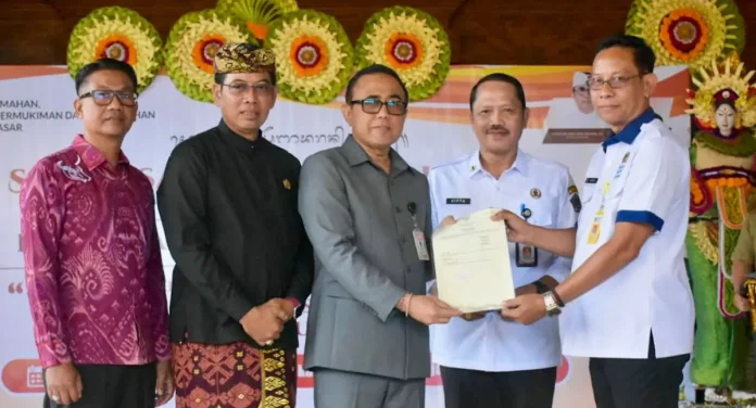 Wali kota Denpasar, I Gusti Ngurah Jaya Negara saat menerima Sertifikat Hak Pakai (SHP) atas nama Pemerintah Kota Denpasar di Kawasan Jalan Karya Makmur serangkaian acara Sosialisasi Penyadaran Publik Pencegahan Tumbuh dan Berkembangnya Pemukiman Kumuh di Kota Denpasar yang digelar di Bale Banjar Pemangkalan, Desa Ubung Kaja, Rabu (25/3/2026).