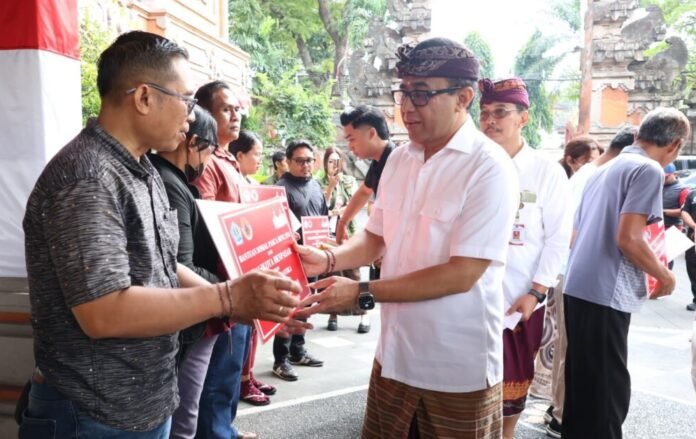 Wali Kota Denpasar, I Gusti Ngurah Jaya Negara saat menyerahkan secara simbolis bantuan pasca bencana kepada 25 perwakilan penerima di lobi Kantor Wali Kota Denpasar, Jumat (14/8/2026) pagi.